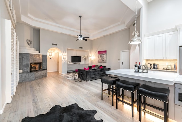 kitchen with a raised ceiling, a breakfast bar area, light wood-style floors, and backsplash