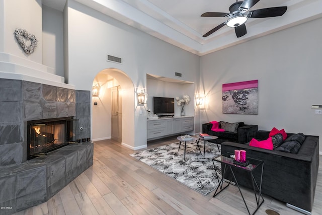 living room with visible vents, wood finished floors, arched walkways, a fireplace, and baseboards