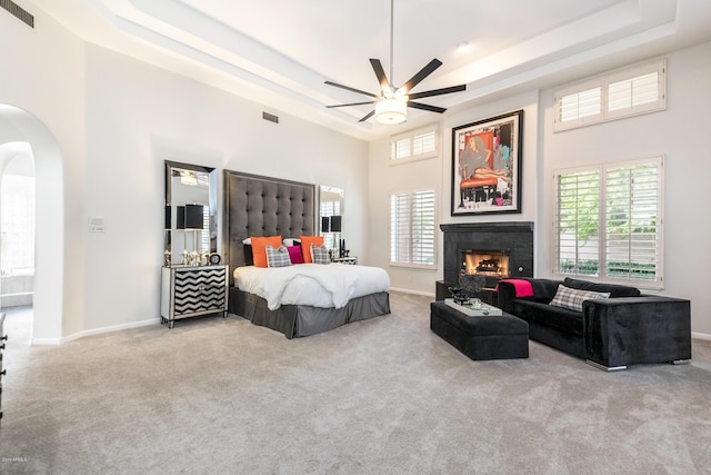 bedroom featuring arched walkways, visible vents, carpet, and a tray ceiling