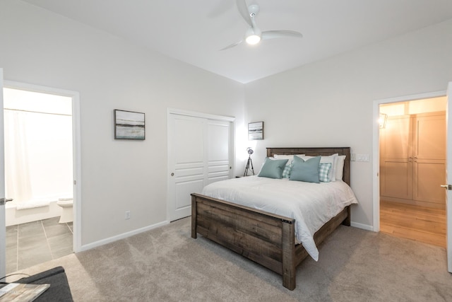 bedroom featuring ceiling fan, baseboards, light carpet, ensuite bathroom, and a closet