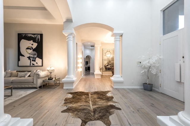 entryway featuring decorative columns, arched walkways, and wood-type flooring