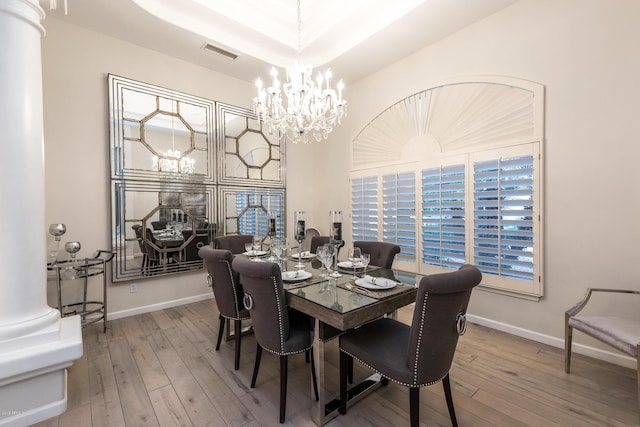 dining area with visible vents, wood-type flooring, and an inviting chandelier