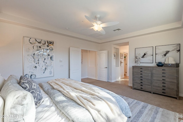 carpeted bedroom with ceiling fan and a tray ceiling