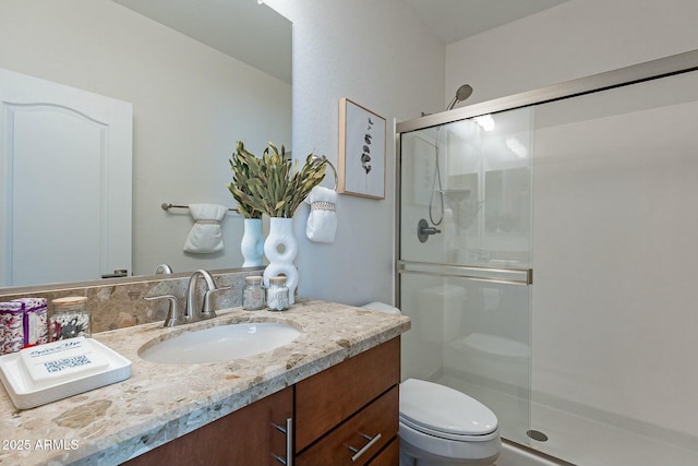 bathroom featuring vanity, toilet, and a shower with shower door