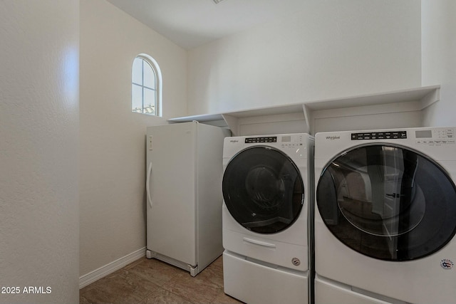 clothes washing area featuring light tile patterned floors and washing machine and dryer