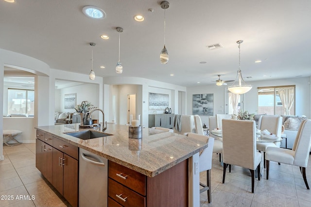 kitchen featuring ceiling fan, dishwasher, sink, hanging light fixtures, and a kitchen island with sink