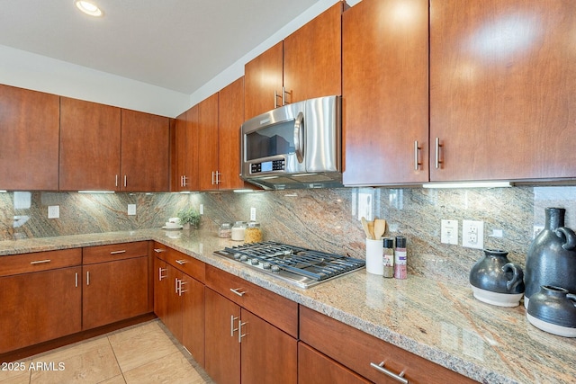 kitchen featuring tasteful backsplash, light stone countertops, light tile patterned flooring, and stainless steel appliances