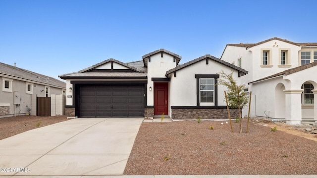 view of front of property featuring driveway, an attached garage, stucco siding, stone siding, and a tile roof