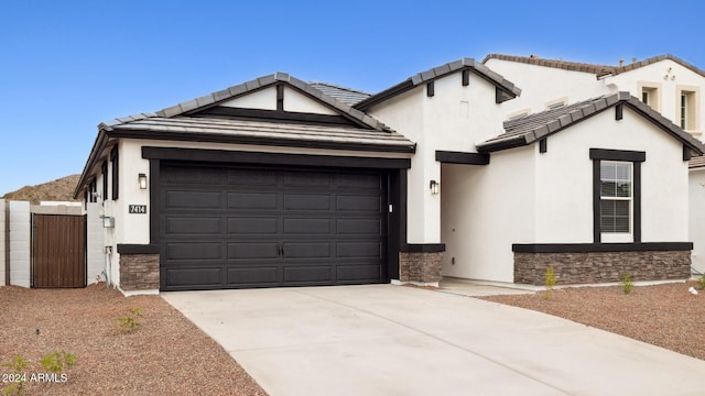 view of front of home with concrete driveway, a tiled roof, stone siding, and stucco siding