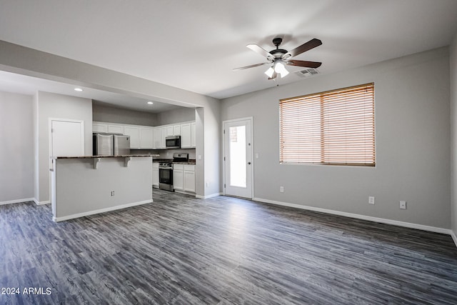 unfurnished living room with dark hardwood / wood-style flooring and ceiling fan