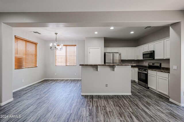 kitchen featuring dark wood-type flooring, white cabinetry, appliances with stainless steel finishes, a kitchen breakfast bar, and a center island