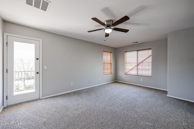 carpeted spare room with ceiling fan and plenty of natural light