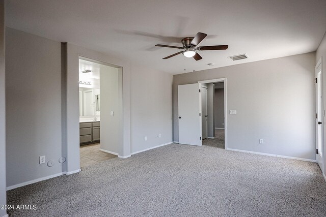 unfurnished bedroom featuring light carpet, connected bathroom, and ceiling fan