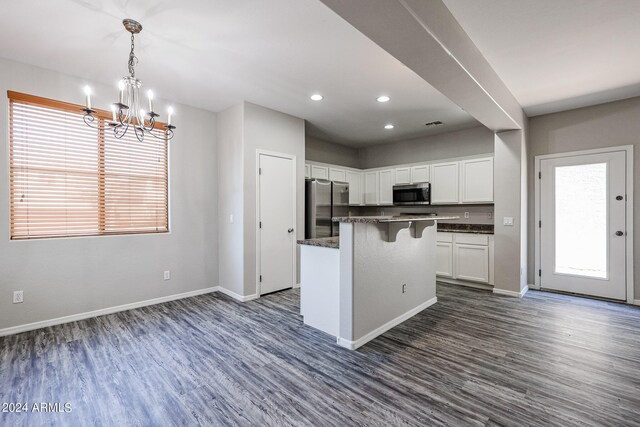 kitchen featuring appliances with stainless steel finishes, white cabinetry, a kitchen bar, a center island, and dark hardwood / wood-style floors