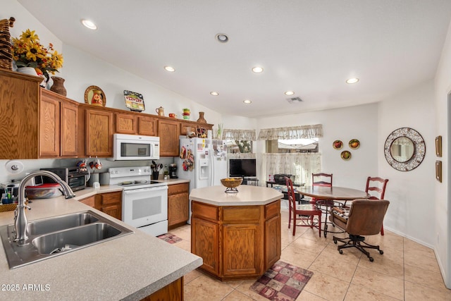 kitchen with a center island, white appliances, light countertops, and a sink