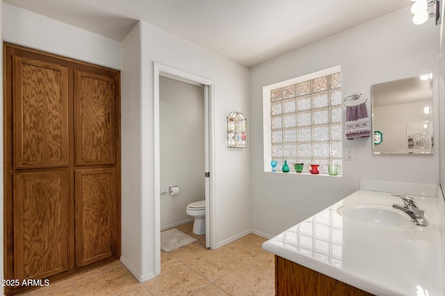 bathroom featuring toilet, tile patterned flooring, baseboards, and vanity