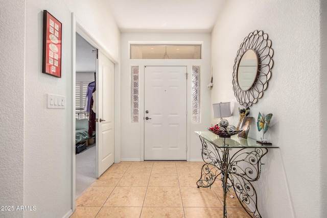 foyer entrance with light tile patterned flooring and baseboards