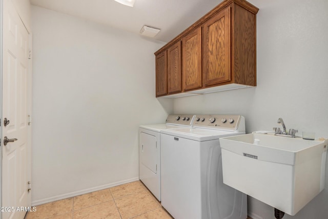 washroom featuring cabinet space, baseboards, washing machine and dryer, a sink, and light tile patterned flooring