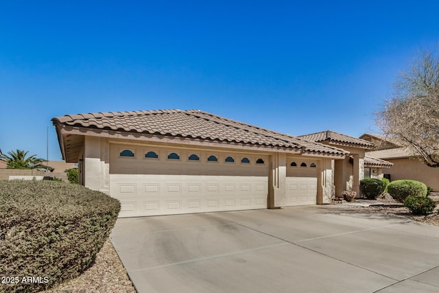 mediterranean / spanish-style house featuring concrete driveway, an attached garage, and stucco siding