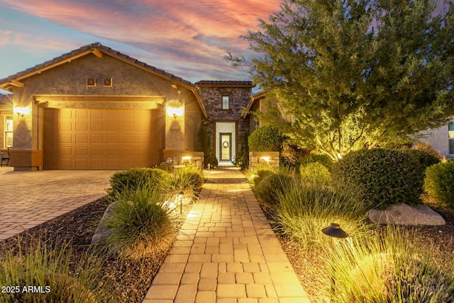 8772 W Brooklite Ln, Peoria, AZ 85383 - view of front of house with an attached garage, stone siding, decorative driveway, stucco siding, and a tile roof