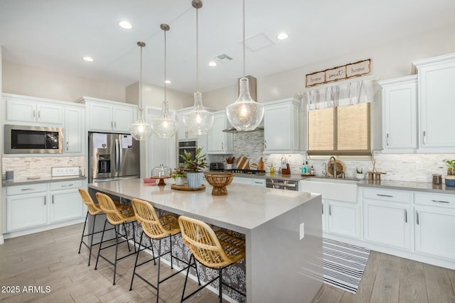 8772 W Brooklite Ln, Peoria, AZ 85383 - kitchen with stainless steel appliances, tasteful backsplash, white cabinetry, a sink, and a center island