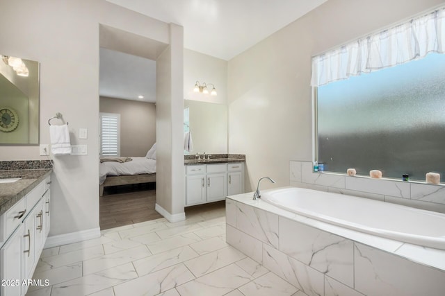 8772 W Brooklite Ln, Peoria, AZ 85383 - ensuite bathroom featuring two vanities, marble finish flooring, a garden tub, and baseboards