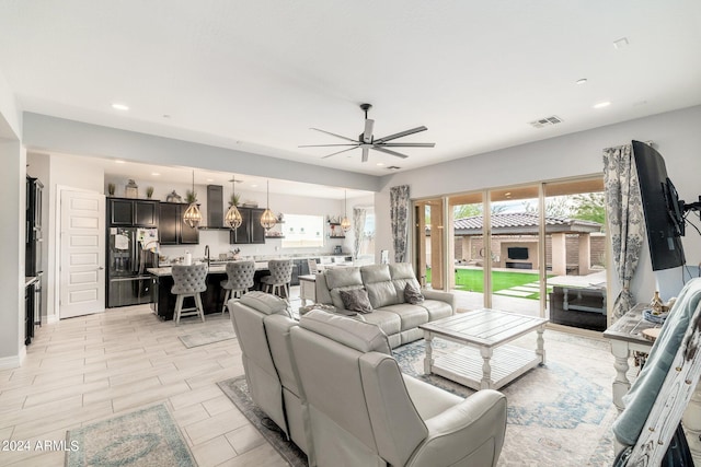 living room featuring ceiling fan, sink, and light tile flooring