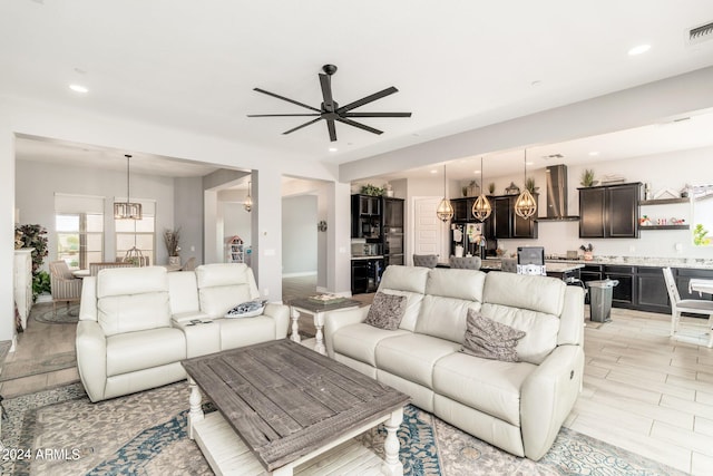 tiled living room with ceiling fan with notable chandelier