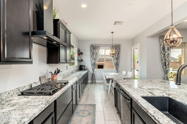 kitchen with pendant lighting, wall chimney range hood, dark brown cabinets, sink, and light stone counters