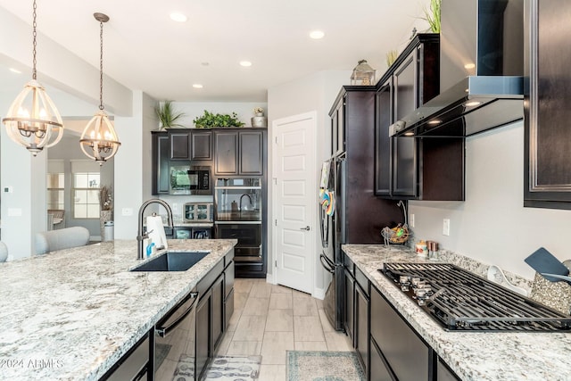 kitchen featuring hanging light fixtures, wall chimney range hood, sink, dark brown cabinetry, and black appliances