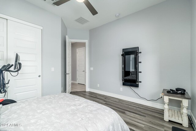 bedroom with dark hardwood / wood-style flooring, ceiling fan, and a closet