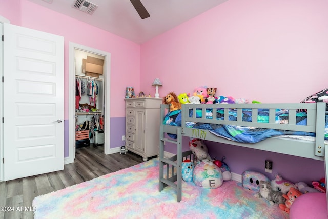 bedroom with a closet, ceiling fan, a walk in closet, and dark wood-type flooring