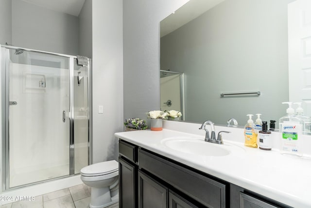 bathroom with toilet, tile flooring, a shower with shower door, and vanity