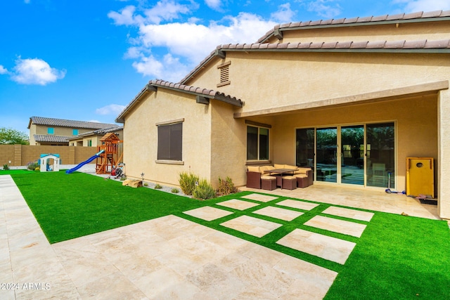 rear view of property featuring a yard, a playground, and a patio area