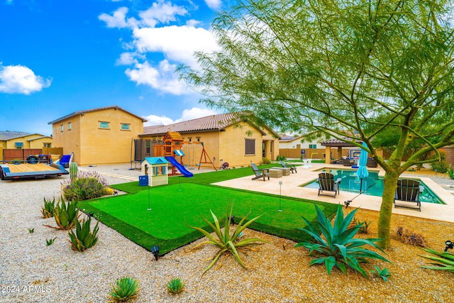 view of yard featuring a pool, a playground, and a patio