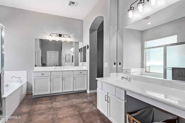 bathroom with a bath, two vanities, and baseboards