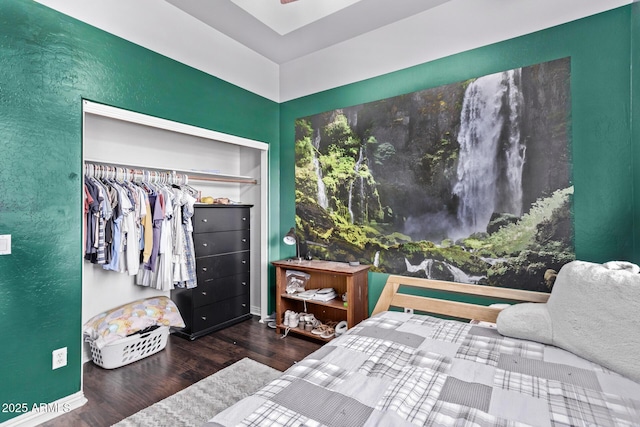 bedroom featuring wood finished floors, a textured wall, baseboards, and a closet