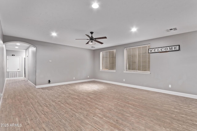spare room featuring recessed lighting, a ceiling fan, light wood-style floors, arched walkways, and baseboards