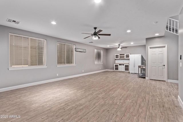unfurnished living room featuring a ceiling fan, light wood-style floors, baseboards, and recessed lighting