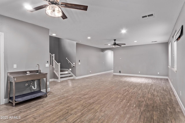 living area with a ceiling fan, wood finished floors, stairs, baseboards, and recessed lighting