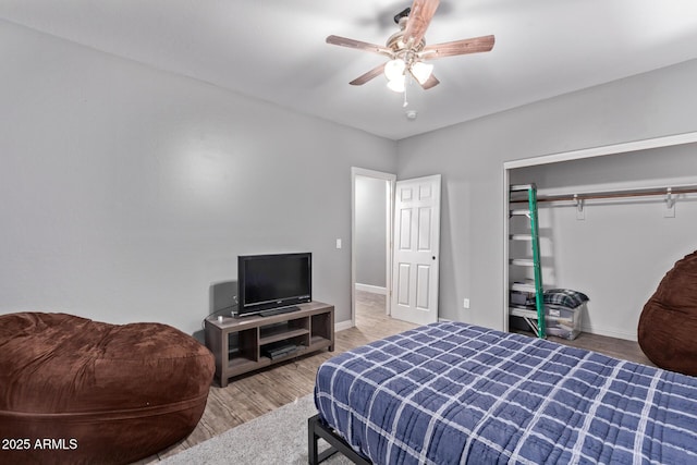 bedroom with wood finished floors, baseboards, a ceiling fan, and a closet