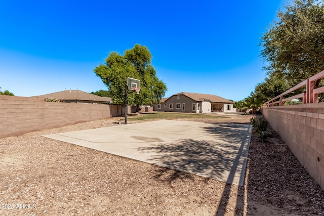view of basketball court featuring a fenced backyard and basketball court