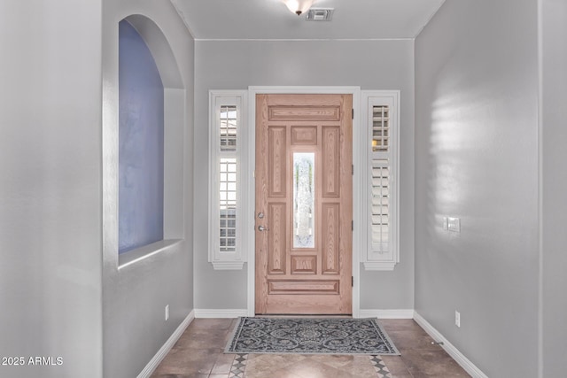 foyer entrance with baseboards and arched walkways