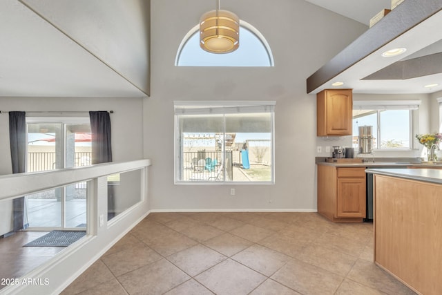 kitchen with light countertops, a towering ceiling, baseboards, and light tile patterned floors