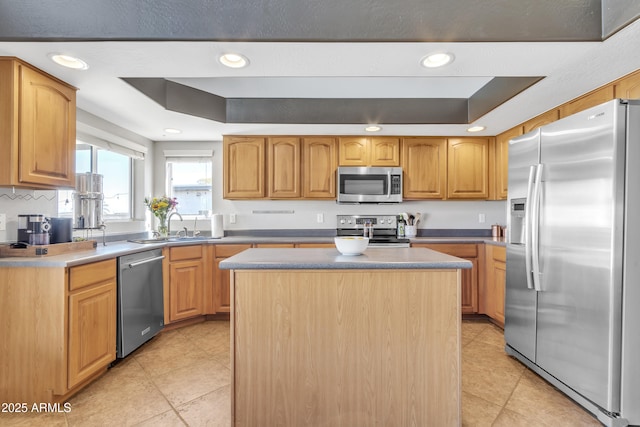 kitchen featuring a raised ceiling, appliances with stainless steel finishes, a center island, a sink, and recessed lighting