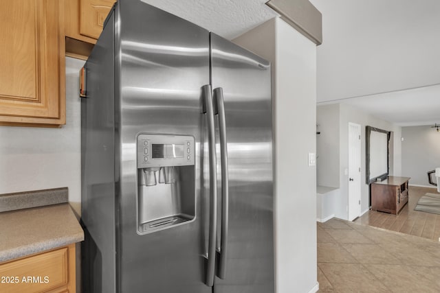 kitchen with light countertops, stainless steel fridge, baseboards, and light tile patterned floors