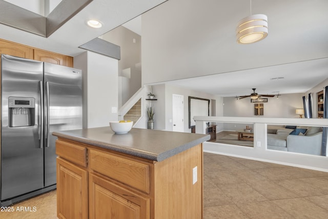 kitchen featuring a center island, light tile patterned floors, dark countertops, ceiling fan, and stainless steel fridge with ice dispenser