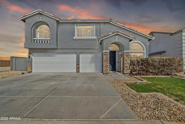 mediterranean / spanish-style home with an attached garage, a tile roof, and concrete driveway