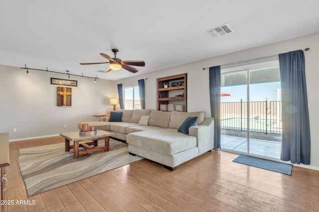 living area with light wood-style flooring, a ceiling fan, visible vents, and a healthy amount of sunlight