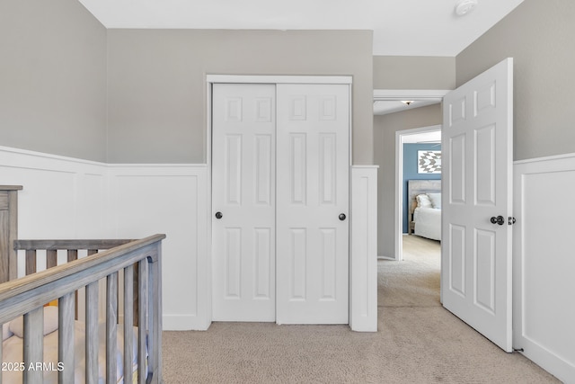 carpeted bedroom featuring a closet, a wainscoted wall, and a decorative wall